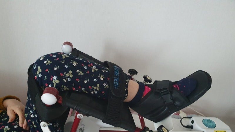 집 침대에서 CPM으로 무릎 재활을 하는 모습